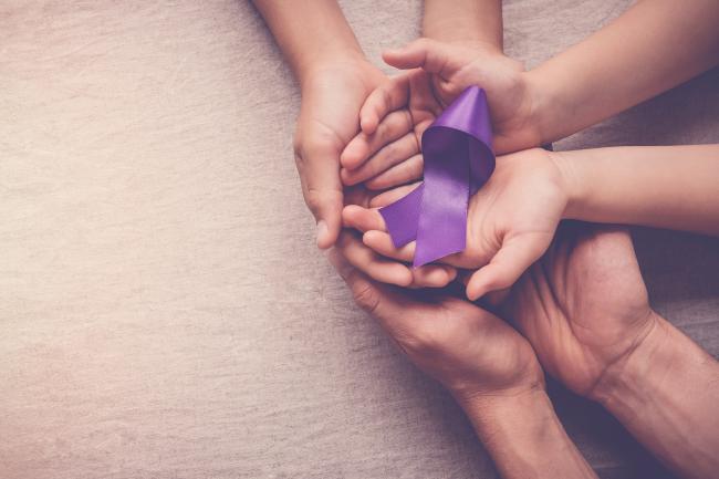 Family hands holding DV awareness purple ribbon